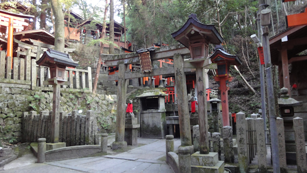 a stone torri gate amongst lanterns and small stone posts